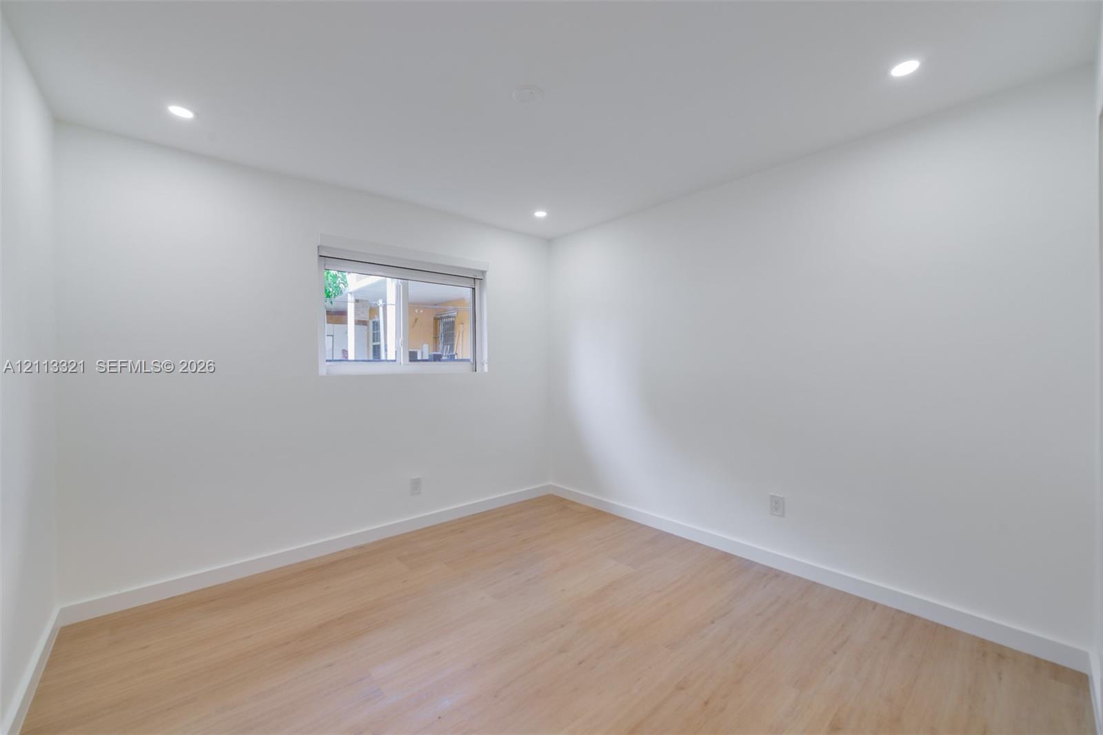 Neutral interior featuring light-tone wood-finish flooring, crisp white walls, and recessed ceiling lighting
