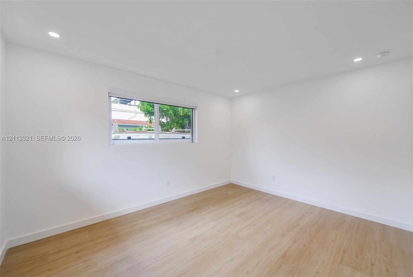 Neutral-toned room featuring wood-finish flooring, recessed lighting, and a single horizontal window
