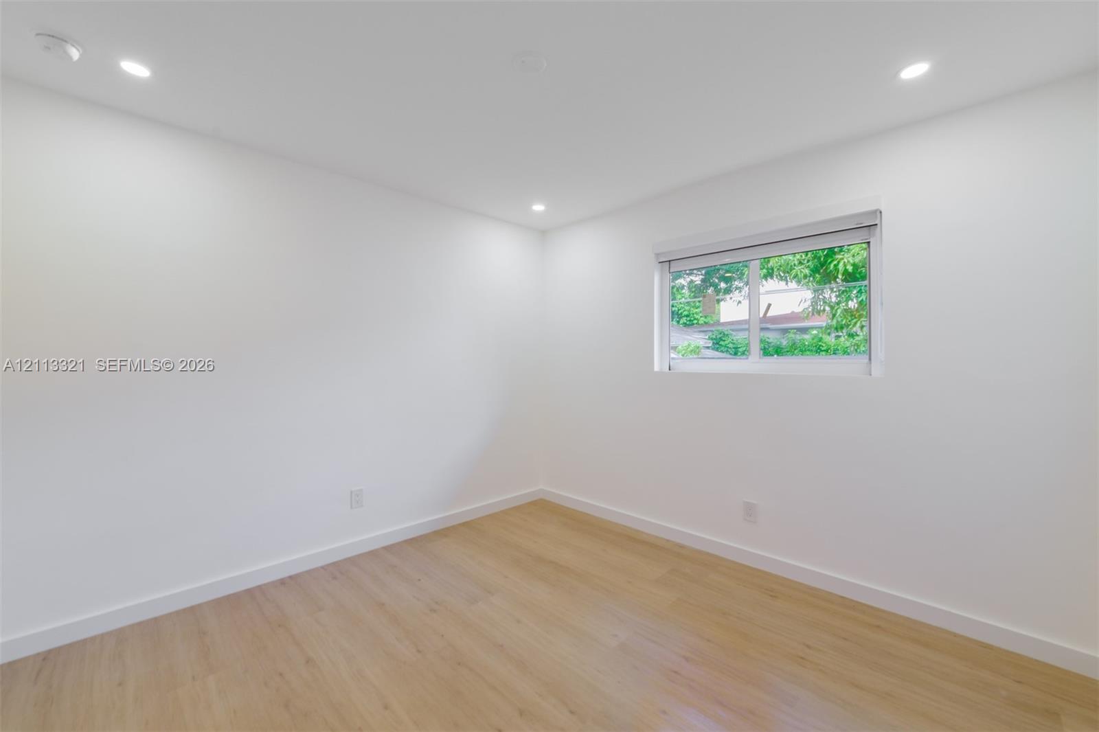 Neutral interior featuring wood-finish flooring, recessed lighting, and a horizontal sliding window