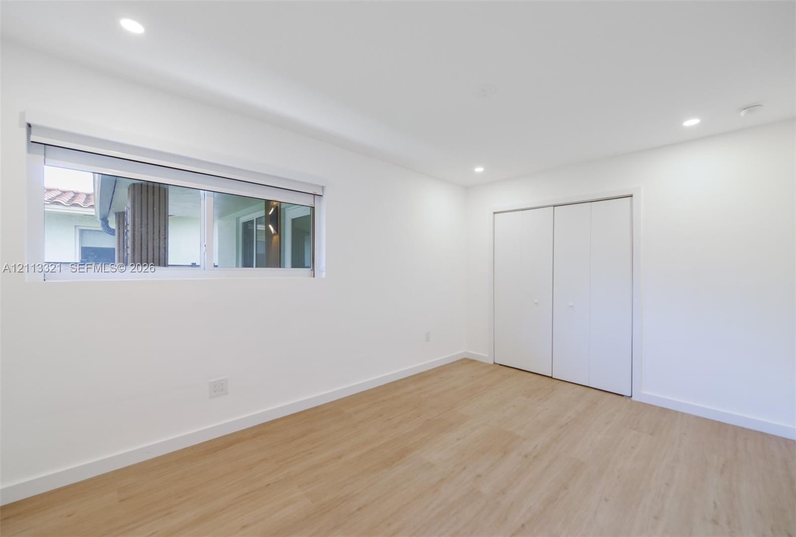 Interior space featuring wood-finish flooring, recessed lighting, a horizontal sliding window, and a built-in closet with double-panel doors