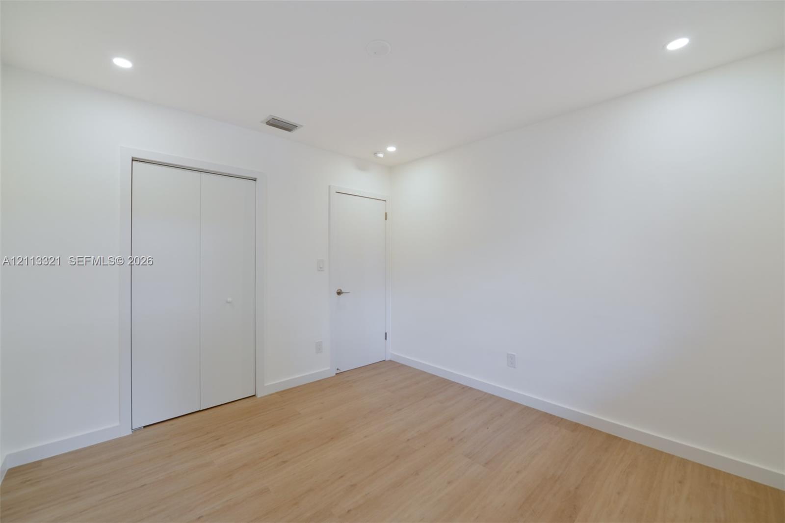 Neutral interior featuring wood-finish flooring, recessed lighting, and white cabinetry doors