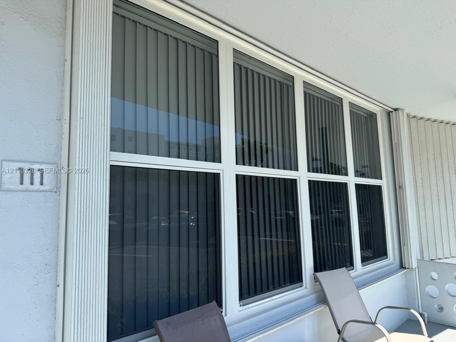 Large, multi-pane window featuring a white frame and integrated vertical blinds