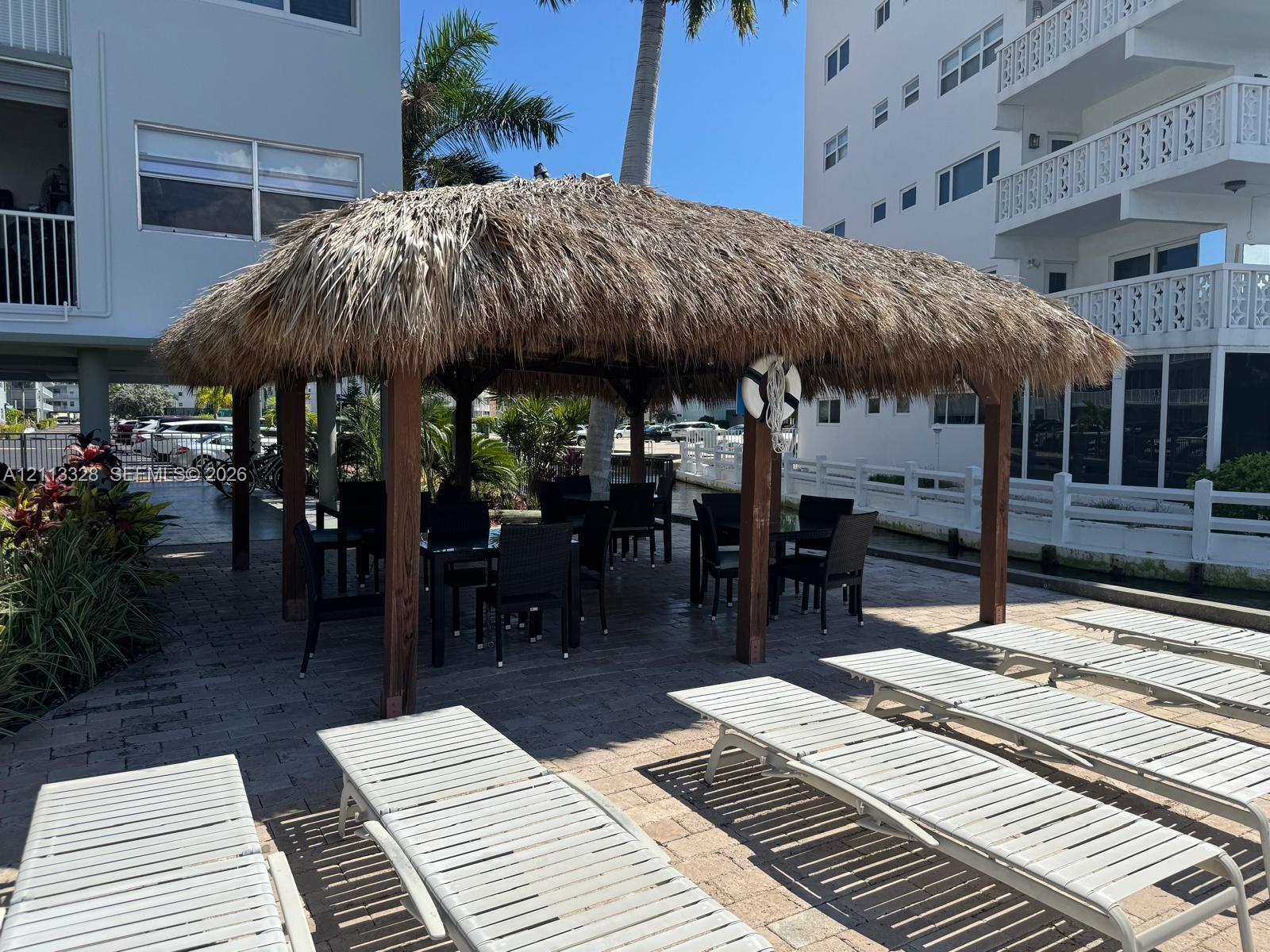 Thatch-roofed gazebo featuring timber support posts set upon a paver patio