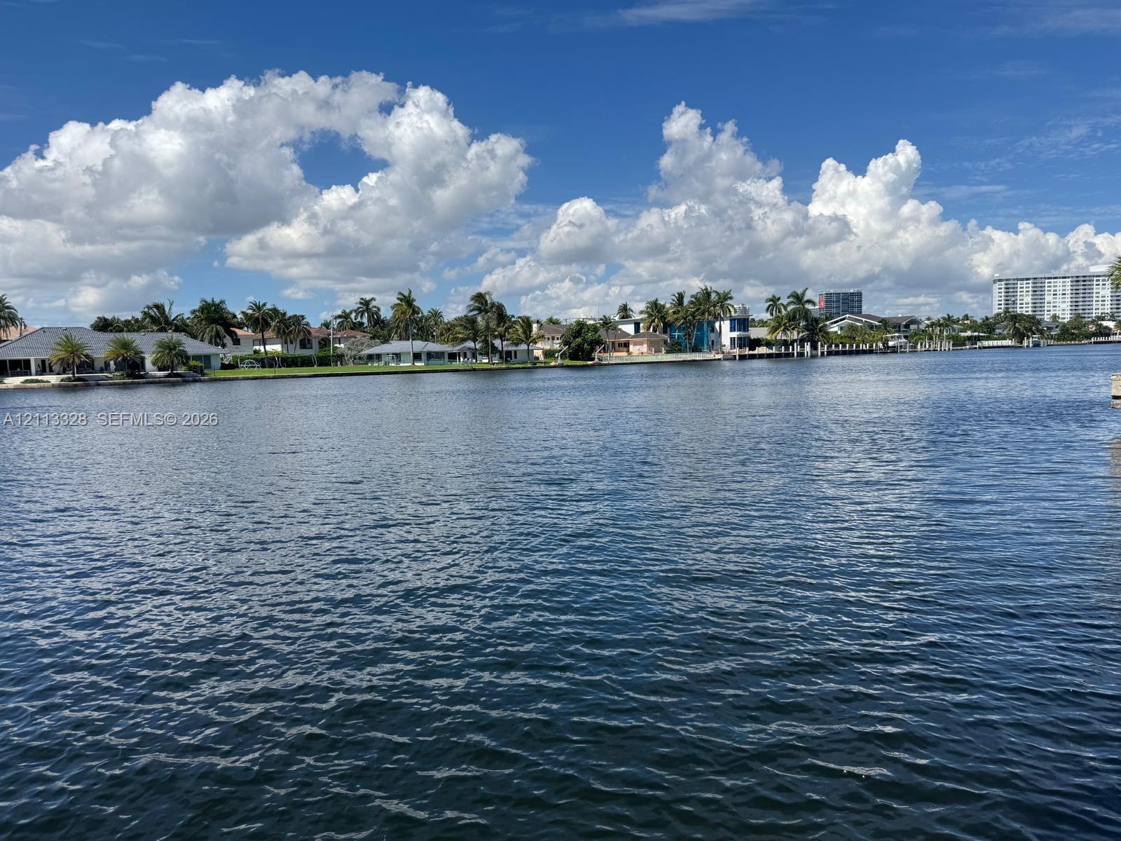 Waterfront property featuring extensive canal frontage, seawall, and tropical landscaping