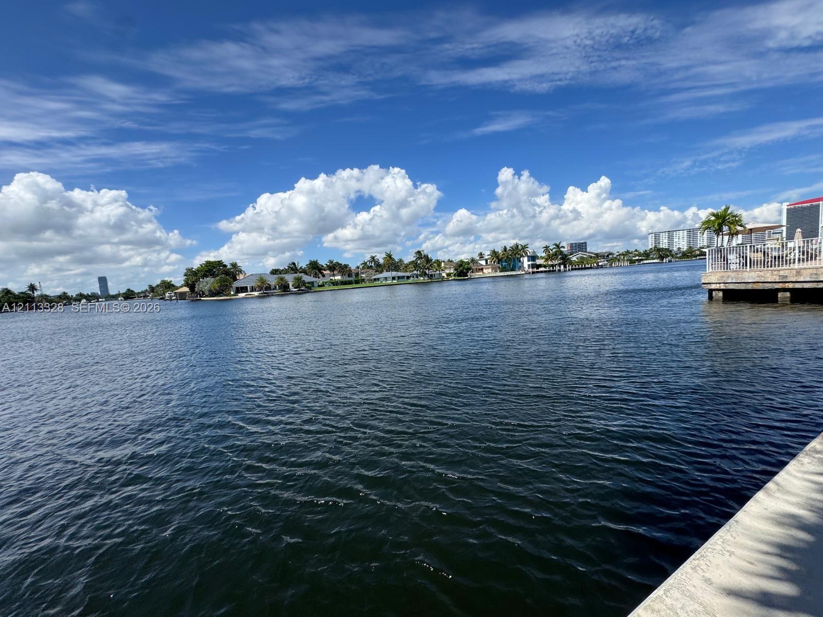 Waterfront property featuring a concrete seawall, metal railing, and paved terrace