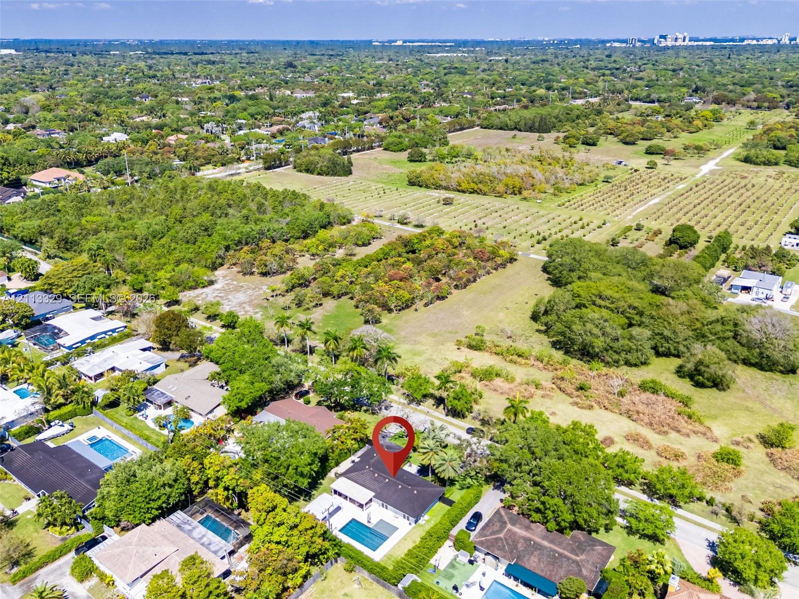 Aerial perspective of a property featuring a private swimming pool, expansive grounds, mature landscaping, and a multi-pitched roofline