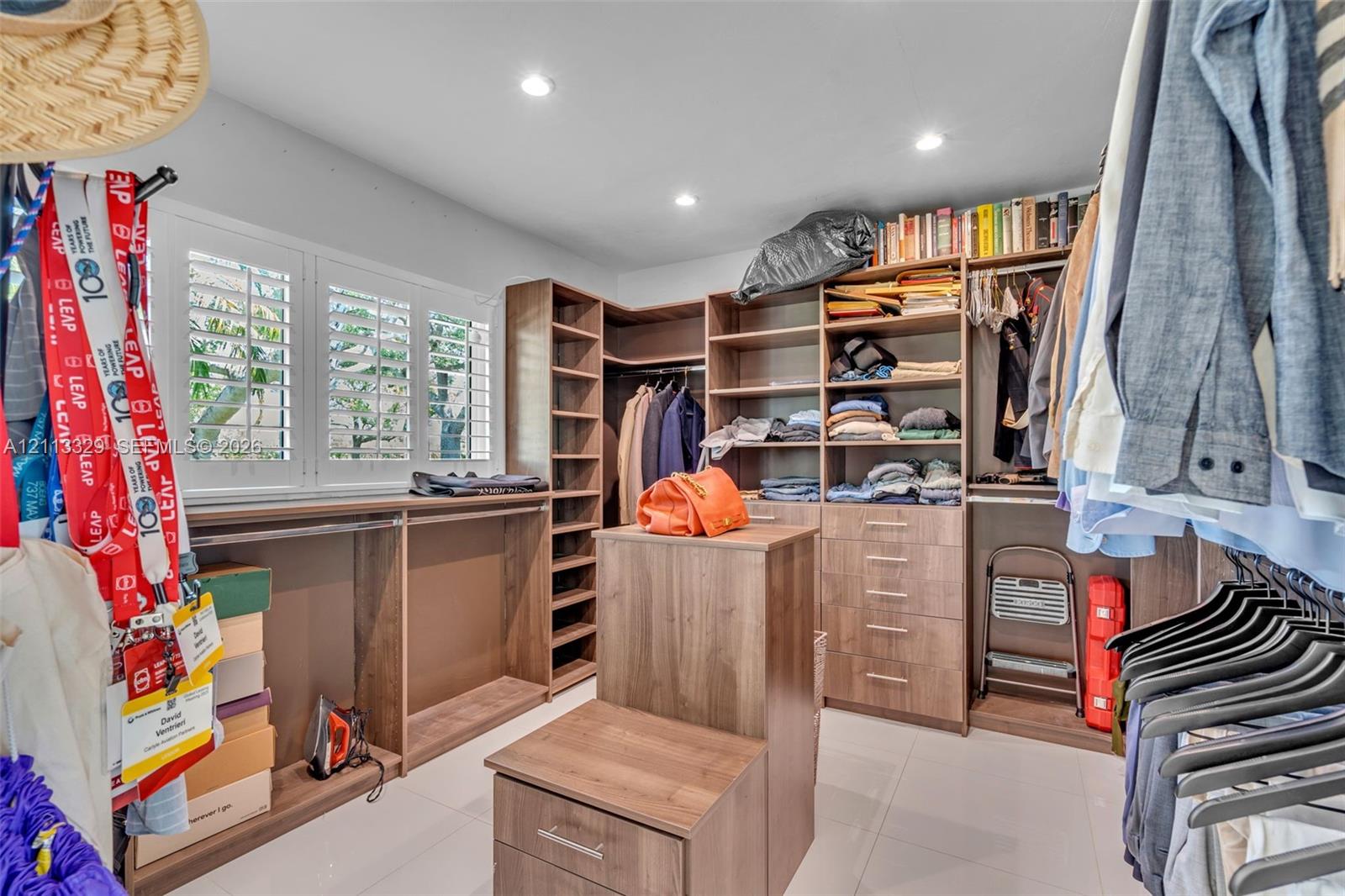Custom walk-in closet featuring extensive built-in cabinetry, integrated drawers, recessed lighting, and white plantation shutters