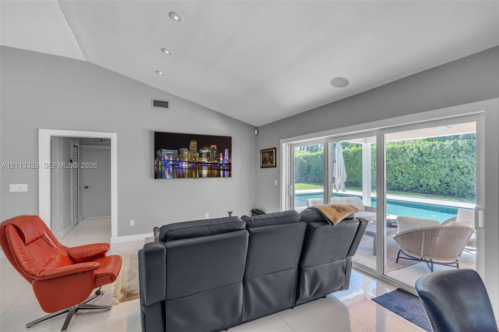 Vaulted ceilings with recessed lighting, tile flooring, and large sliding glass doors providing outdoor access