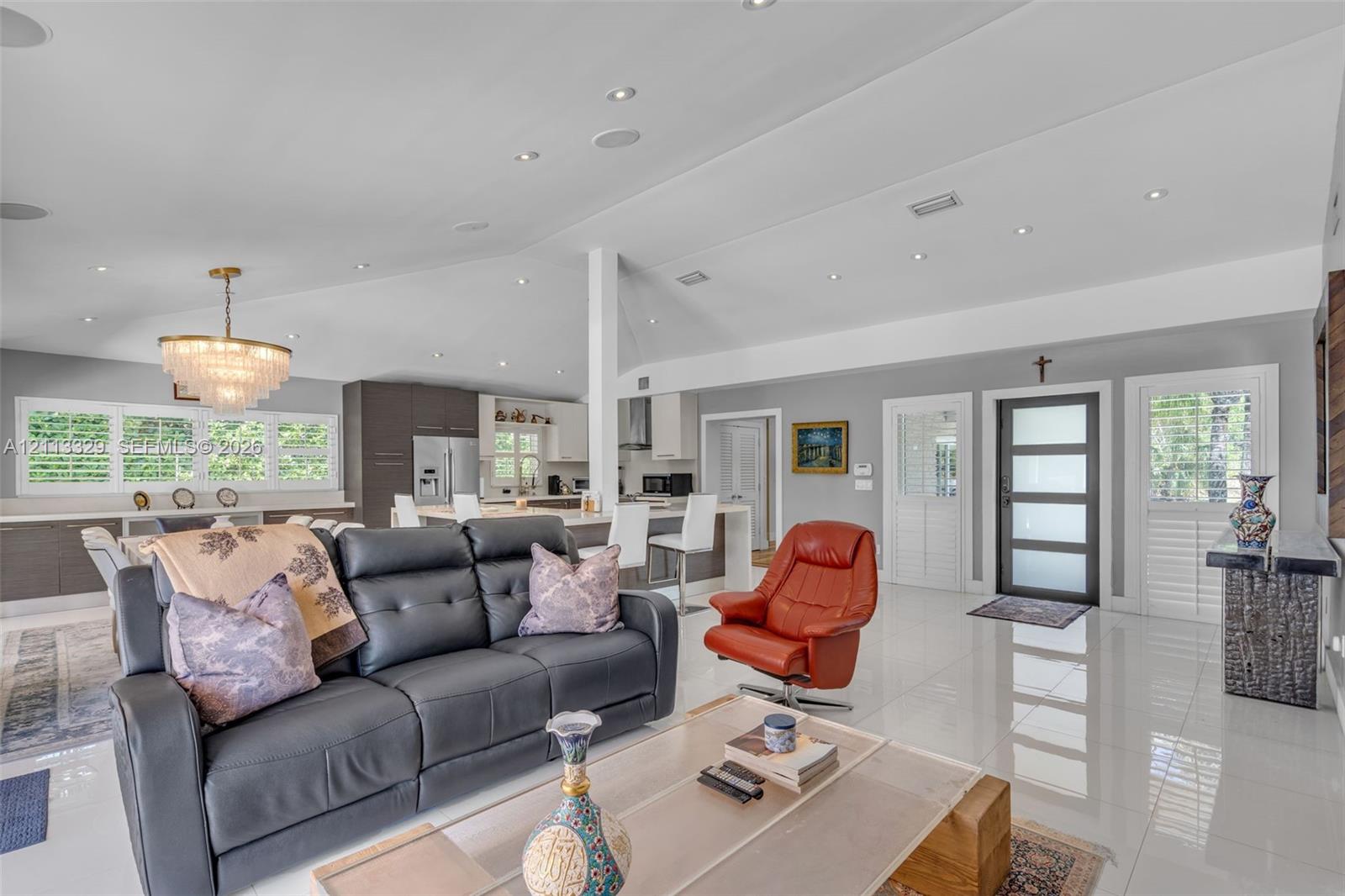 Vaulted ceilings with recessed lighting, tile flooring, tiered crystal chandelier, and exterior door with frosted glass panels