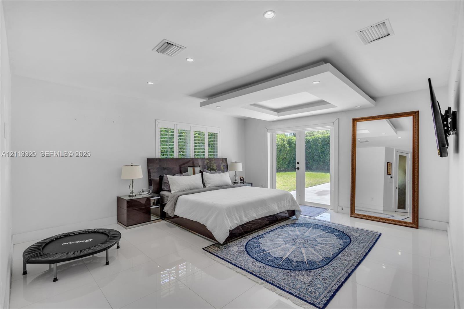 Tray ceiling with recessed lighting, large-format tile flooring, and glass-paned double doors leading to the exterior