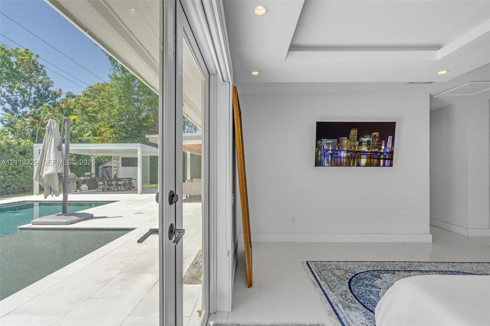 Floor-to-ceiling glass panel doors, tray ceiling with recessed lighting, and polished stone-finish flooring