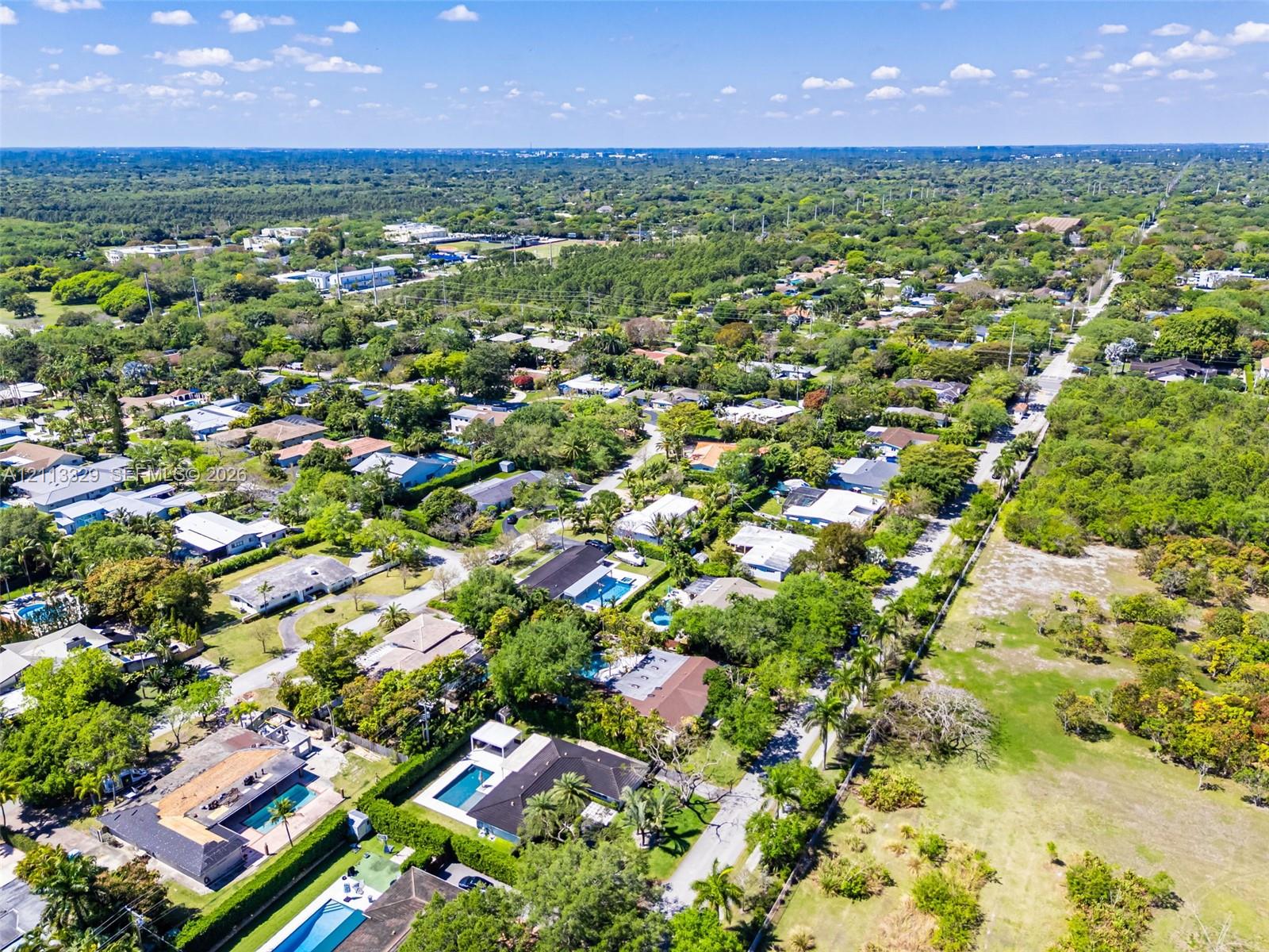 Aerial perspective of the residential grounds featuring mature canopy trees, structured paved street access, and expansive green space
