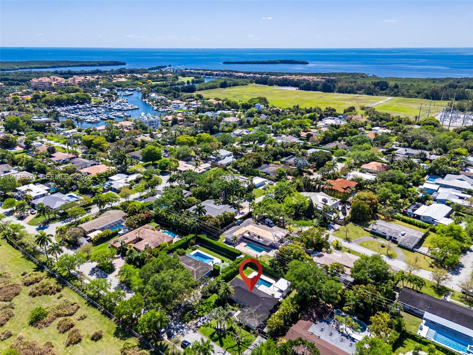 Aerial perspective of a property featuring an in-ground swimming pool, a private screened enclosure, and mature perimeter landscaping