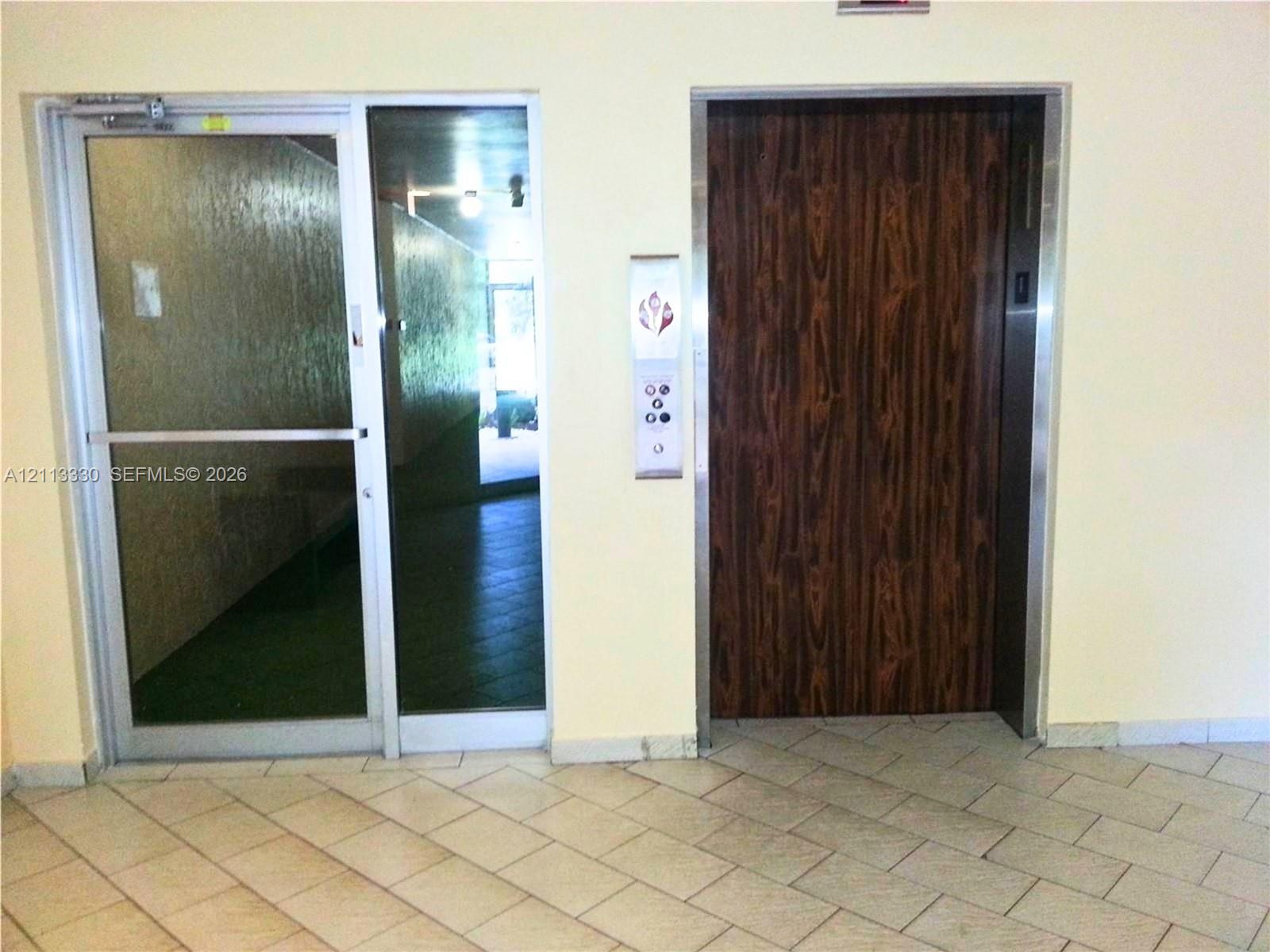Commercial elevator featuring wood-finish paneling, metal frame, and vertical control panel, accompanied by a glass door with a metal frame Commercial elevator featuring wood-finish paneling, metal frame, and vertical control panel, accompanied by a glass door with a metal frame