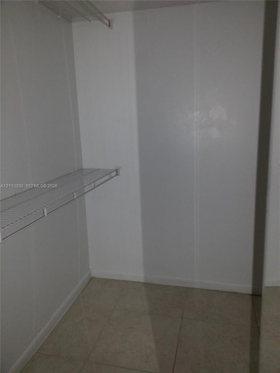 Storage space featuring white walls, large-format tile flooring, and metal wire shelving Storage space featuring white walls, large-format tile flooring, and metal wire shelving
