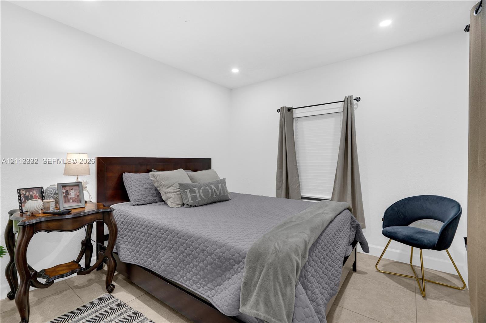 Neutral-toned walls, recessed lighting, tile flooring, and a single window featuring a curtain rod