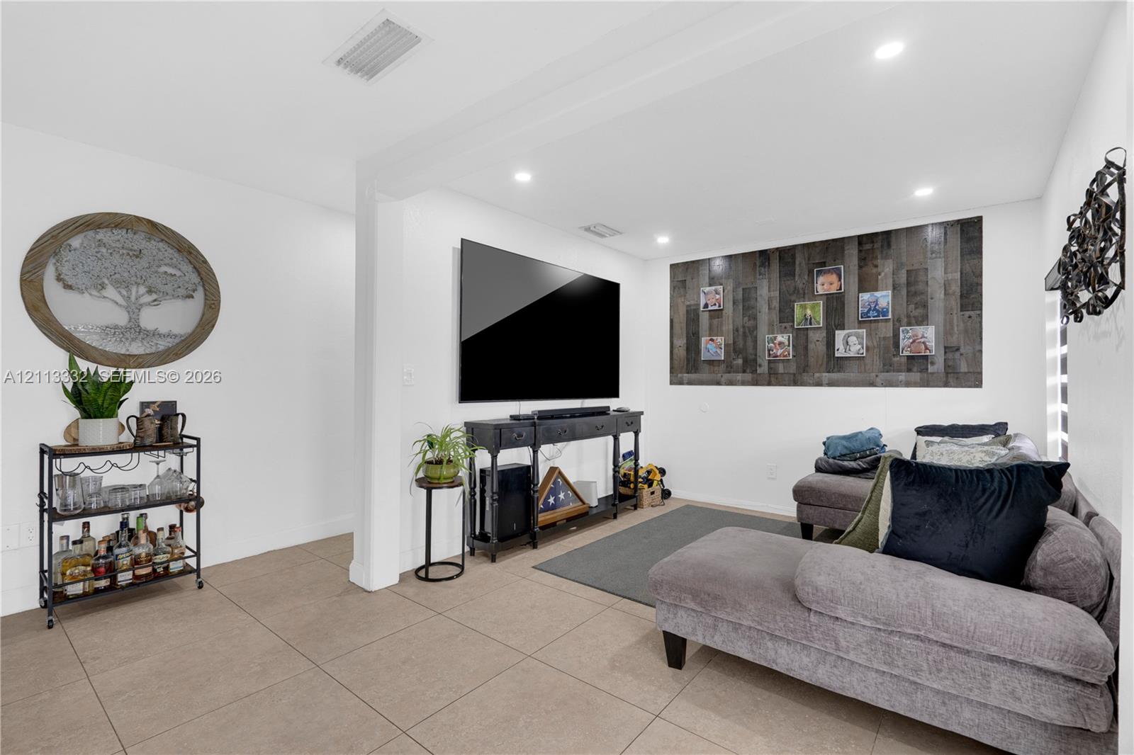 Neutral-toned tile flooring, recessed ceiling lighting, and a textured wood-plank accent wall