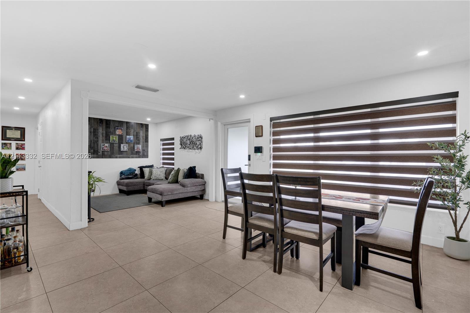 Open-concept interior featuring large-format tile flooring, recessed lighting, and horizontal window shades