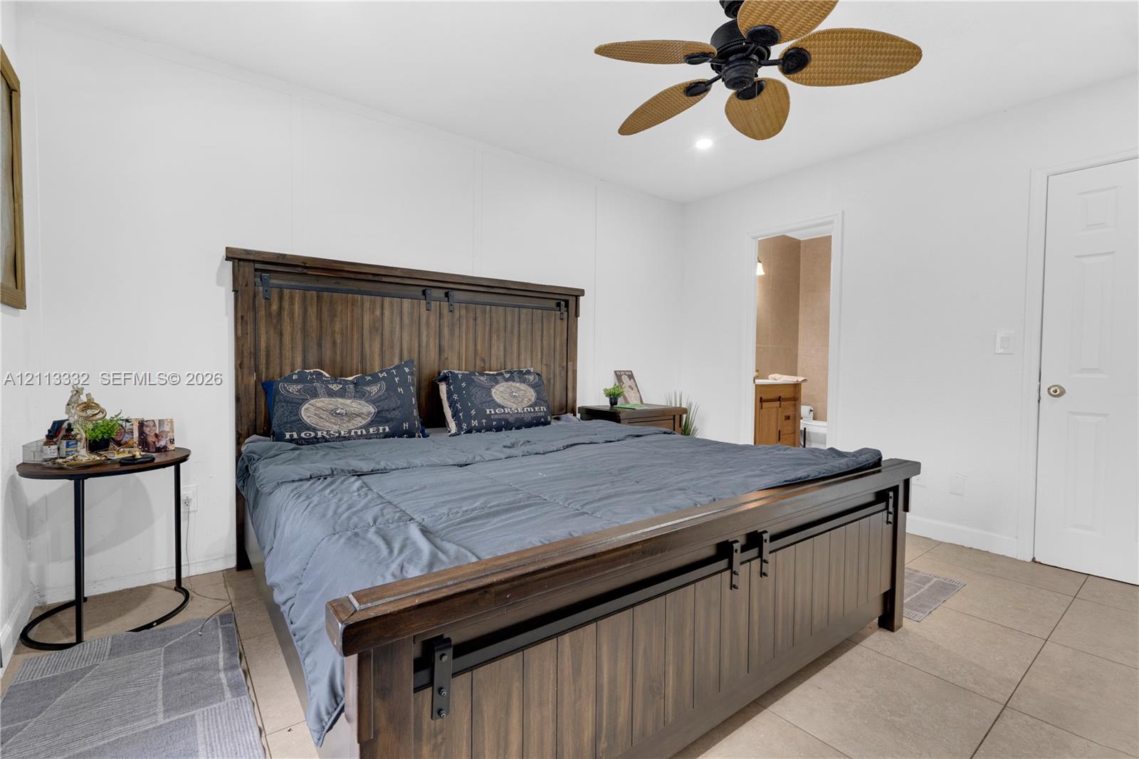Neutral-toned room featuring large-format tile flooring, a multi-blade ceiling fan, and a six-panel interior door