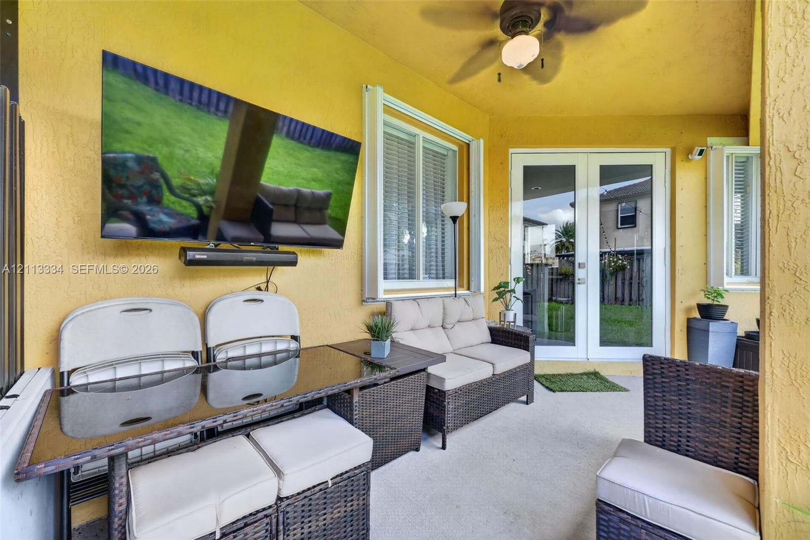 Covered patio featuring a concrete floor, ceiling fan, and double glass-paned doors