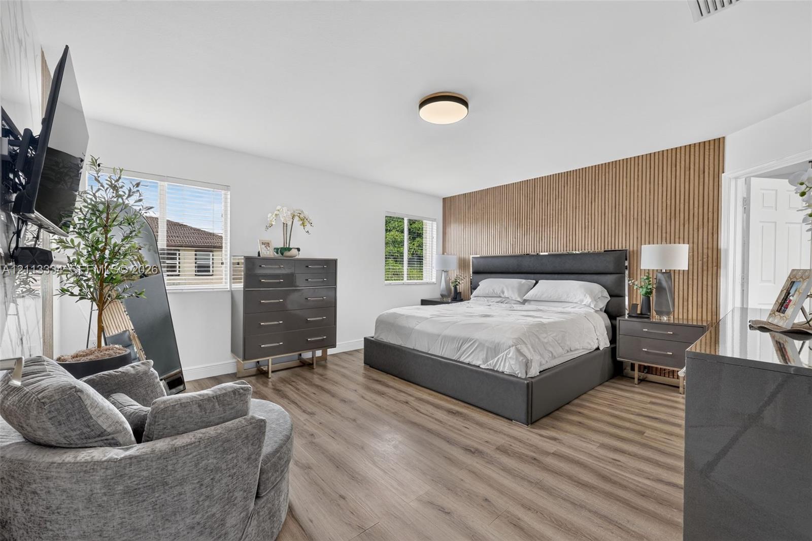 Wood-finish flooring, vertical wood-slat accent wall, and flush-mount ceiling lighting
