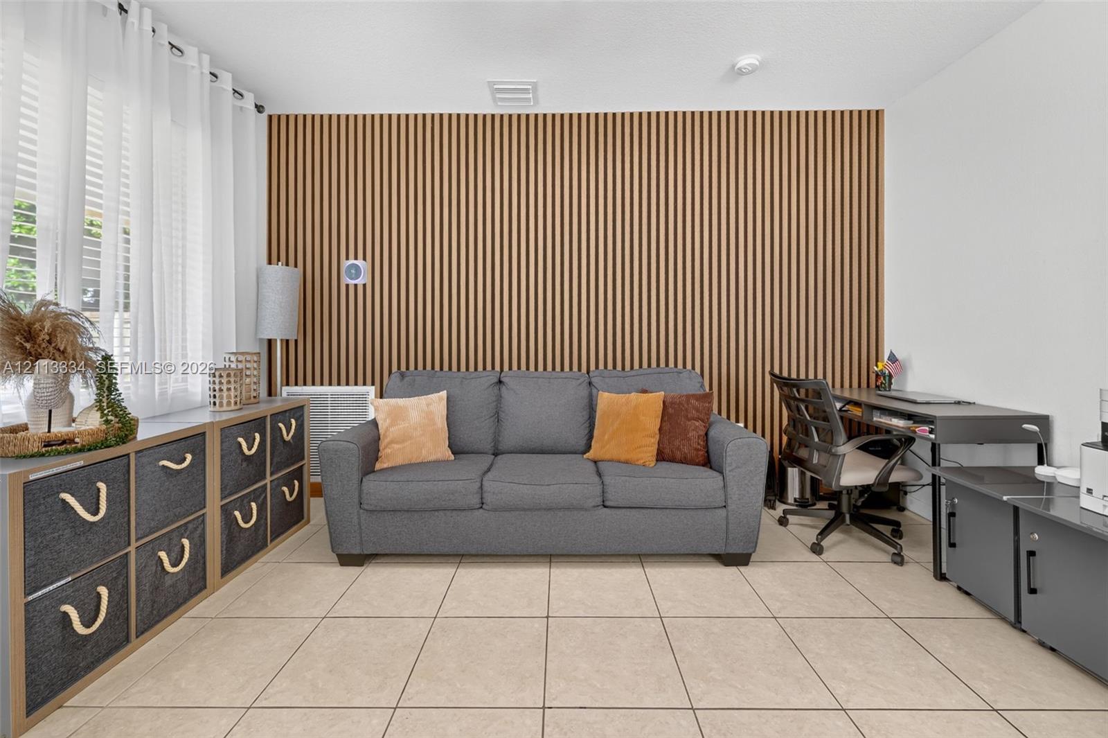 Vertical wood-slat accent wall featuring a linear texture, complemented by neutral tile flooring and large windows with integrated curtain hardware