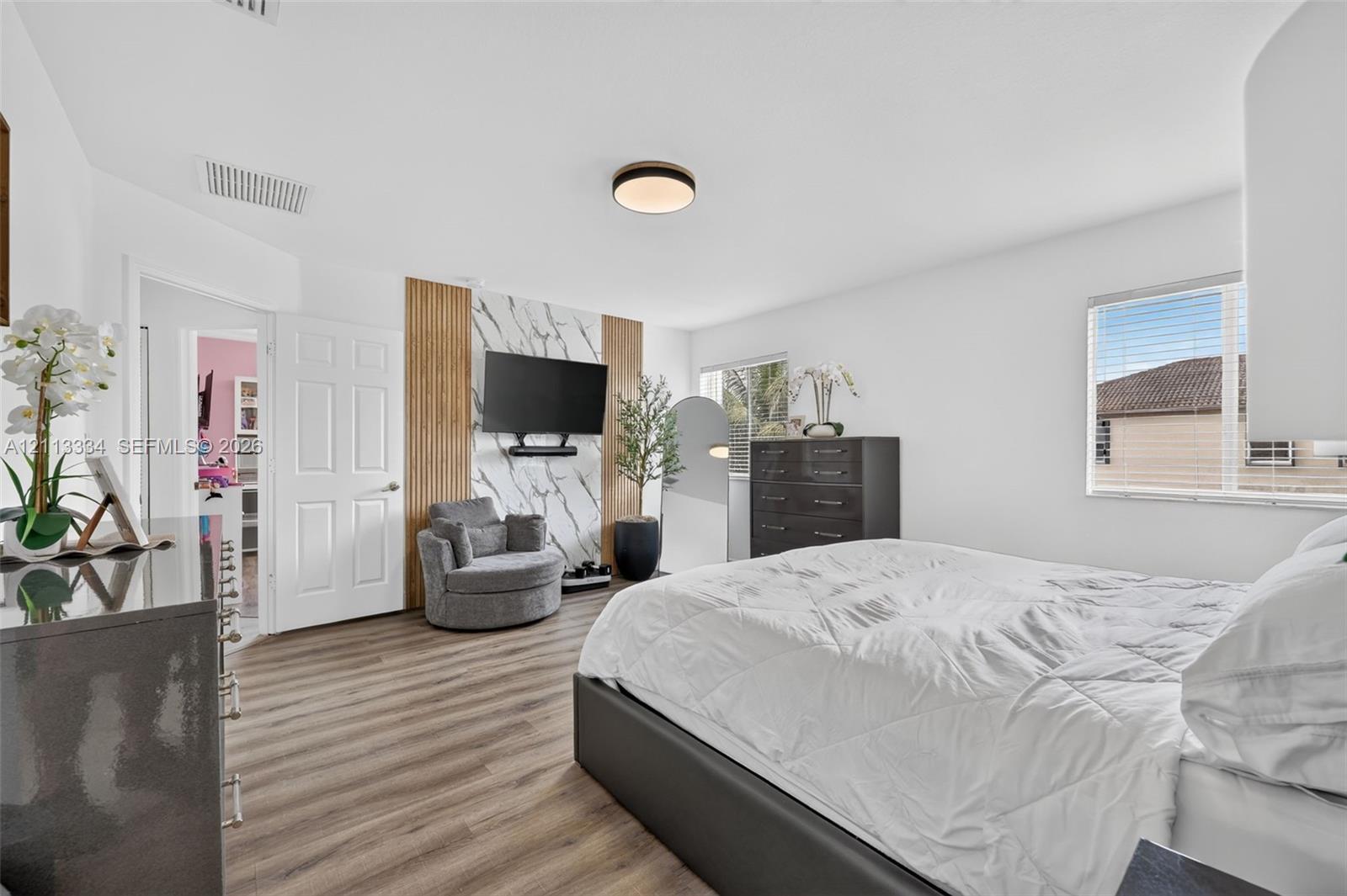 Room featuring wood-finish flooring, accent wall with stone-patterned slab and vertical wood slats, and flush-mount circular lighting