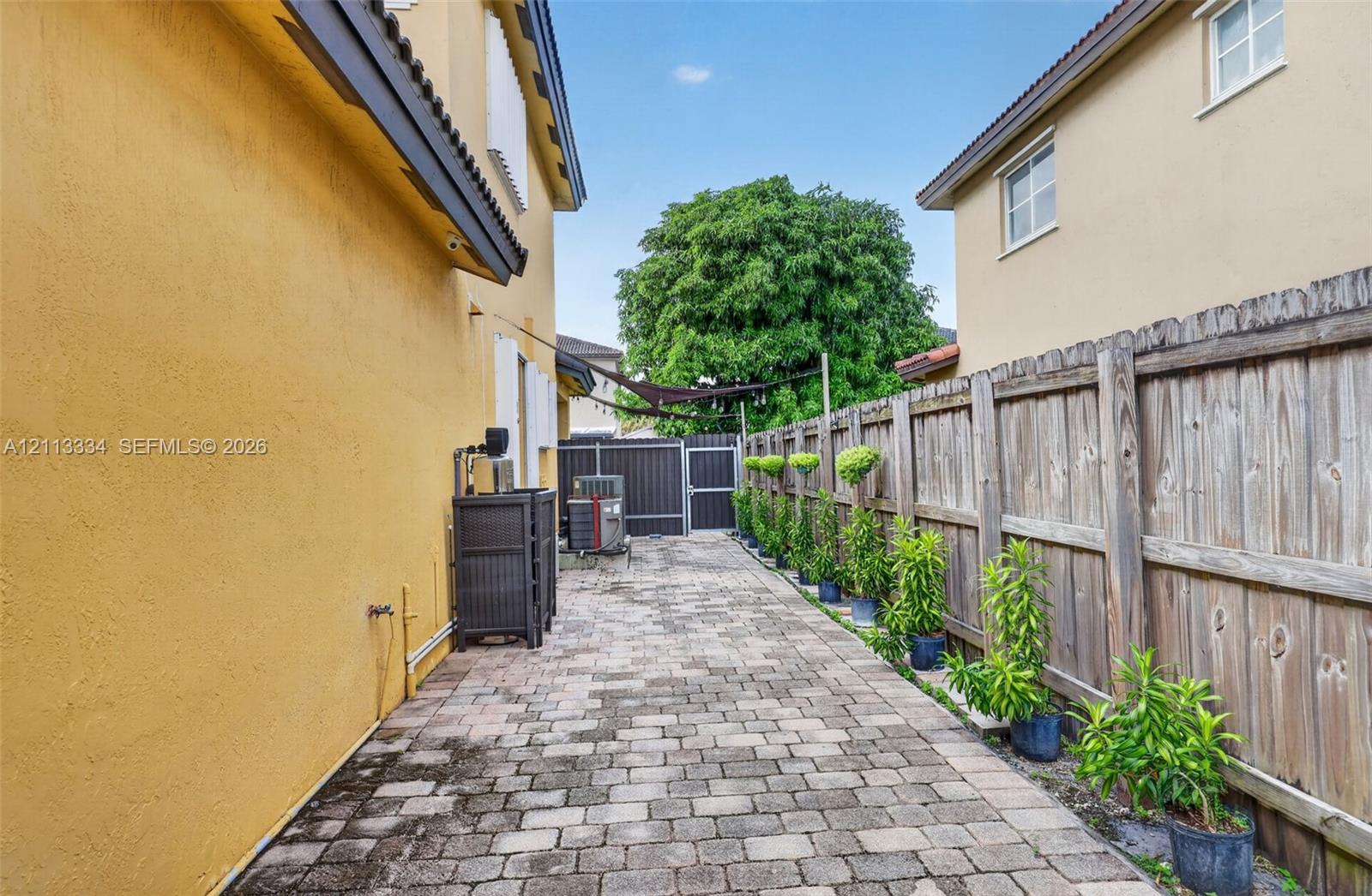 Side yard featuring paver patio, wood privacy fencing, and structured landscaping