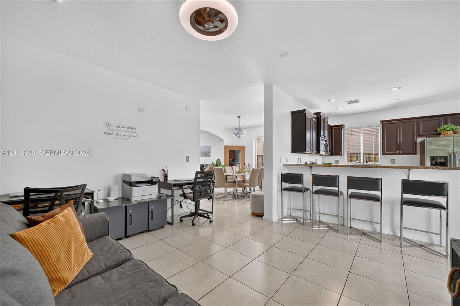 Open-concept living space featuring large-format tile flooring, a kitchen breakfast bar, recessed lighting, and a contemporary ceiling fan