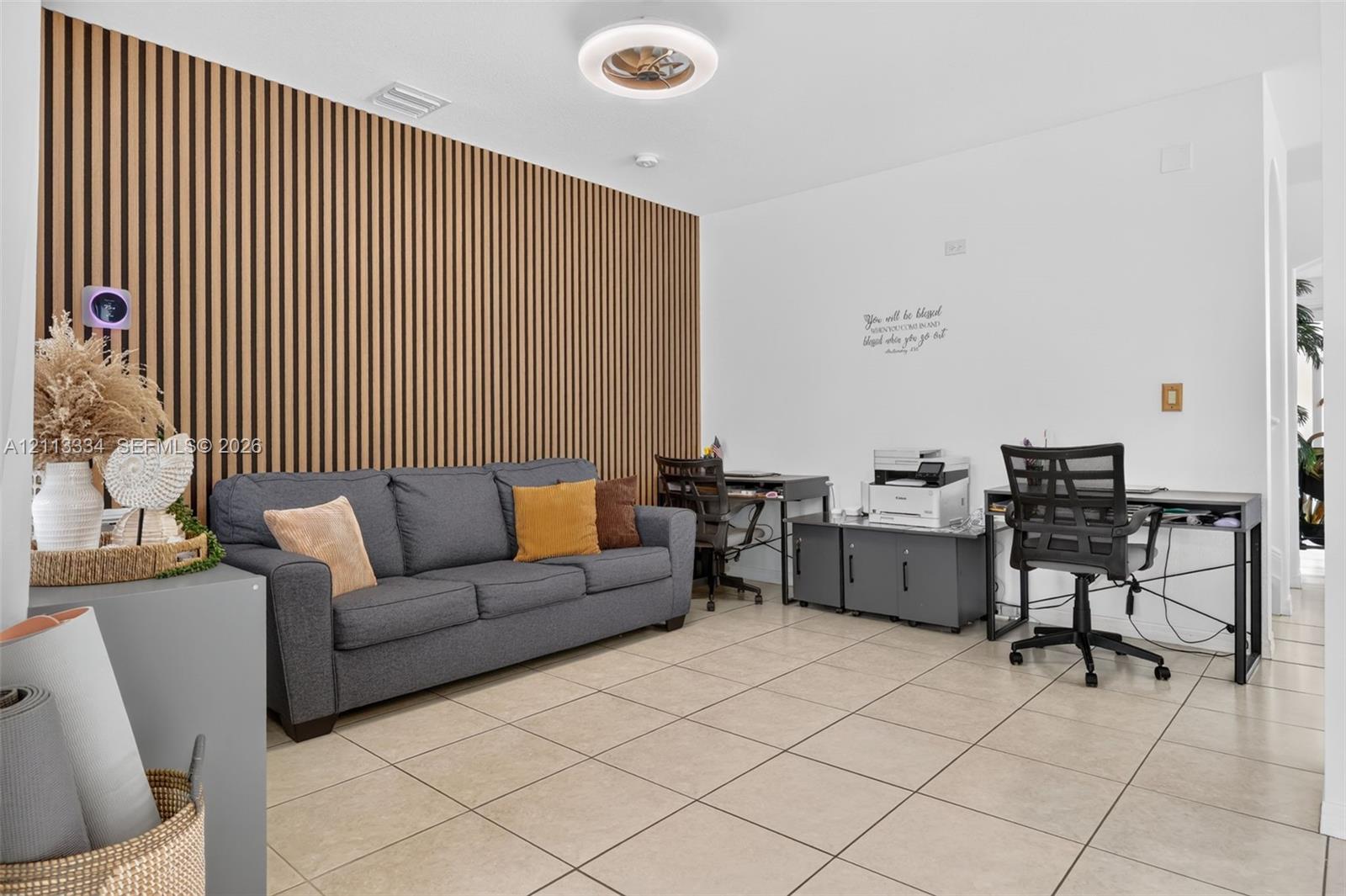 Vertical wood-slat accent wall, neutral ceramic tile flooring, and circular LED ceiling light fixture