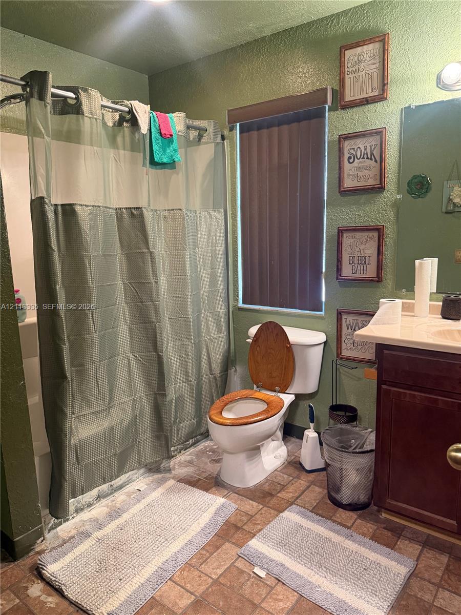 Bathroom featuring a shower-tub combination, wall-mounted vanity with a solid-surface countertop, and ceramic tile flooring Bathroom featuring a shower-tub combination, wall-mounted vanity with a solid-surface countertop, and ceramic tile flooring