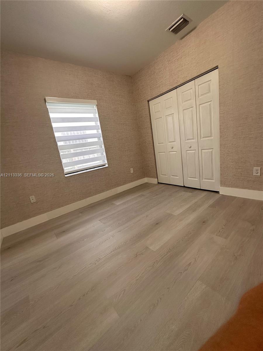 Room featuring textured wall coverings, wood-finish flooring, and a multi-panel closet door