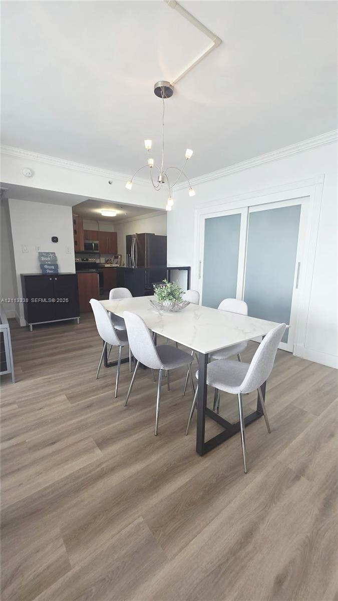 Wood-finish flooring, multi-arm chrome chandelier, and sliding doors with frosted glass panels