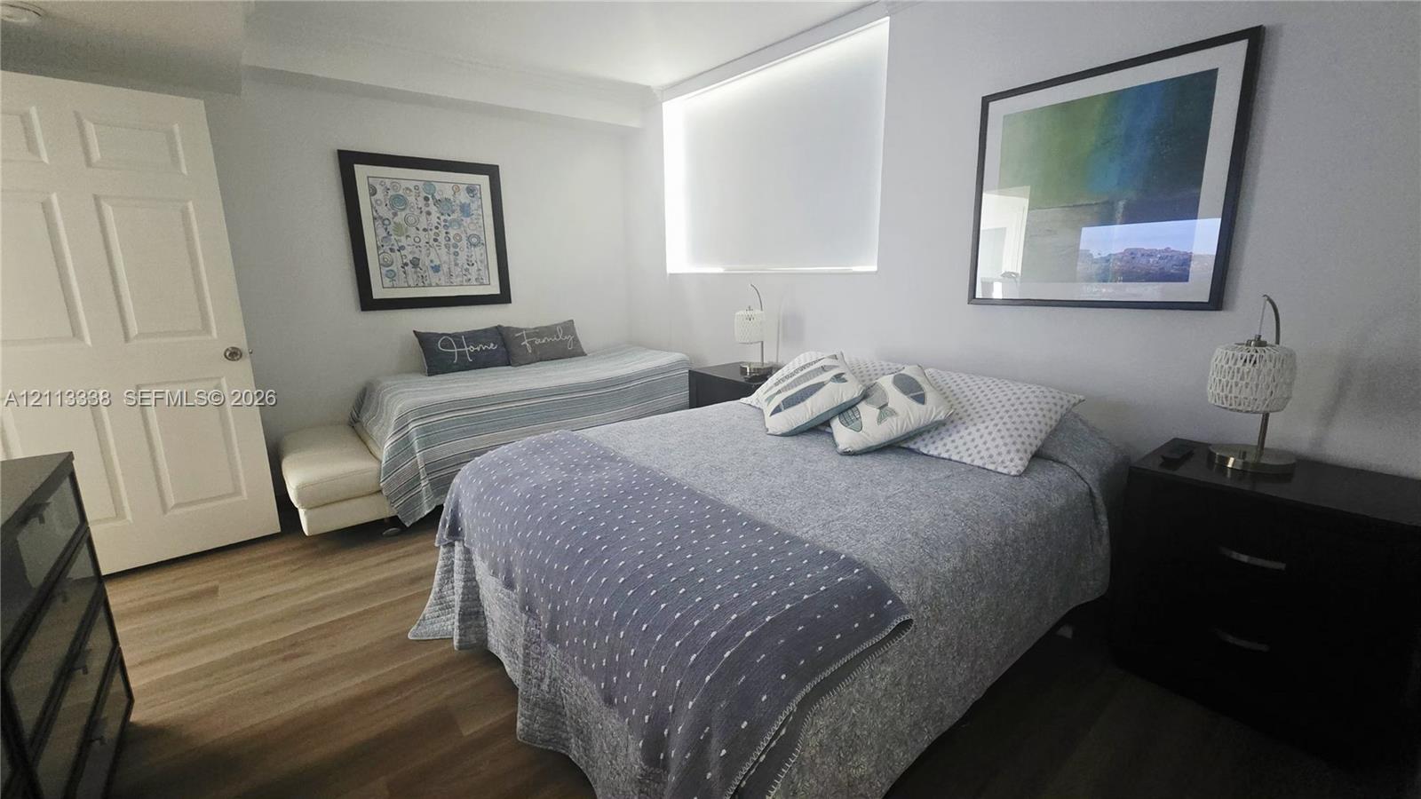 Room featuring wood-finish flooring, a six-panel door, and a horizontal rectangular window