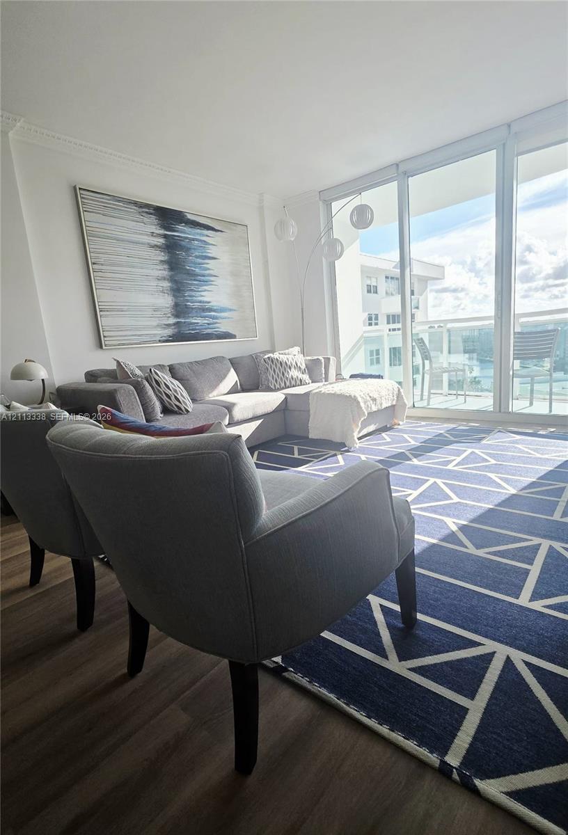 Floor-to-ceiling glass panel windows, wood-finish flooring, crown molding, and private balcony access