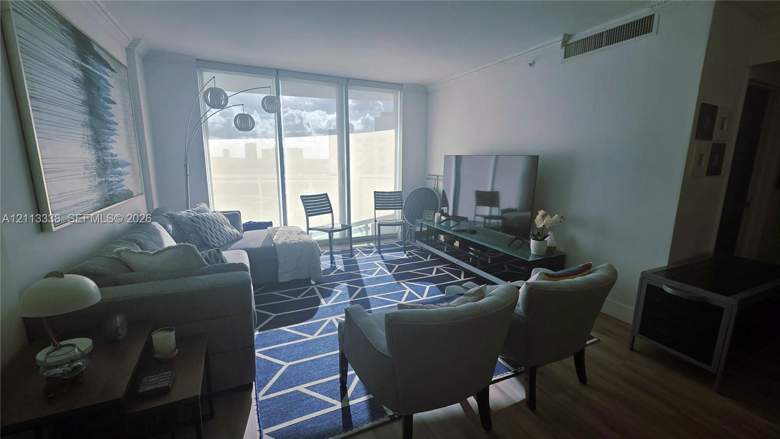 Floor-to-ceiling windows, wood-finish flooring, and crisp neutral wall finishes