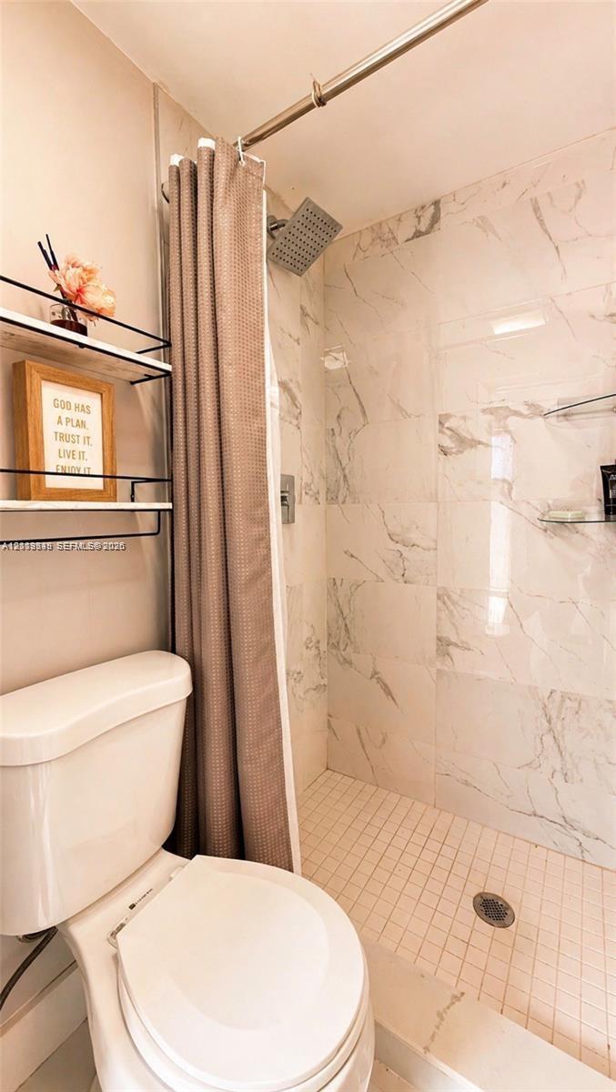Full-height tiled shower surround, square rainfall showerhead, and integrated glass shelving