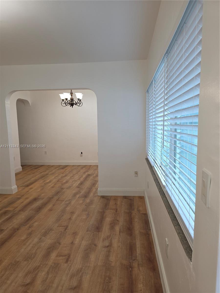 Arched doorway, multi-light hanging chandelier, and windows fitted with horizontal blinds