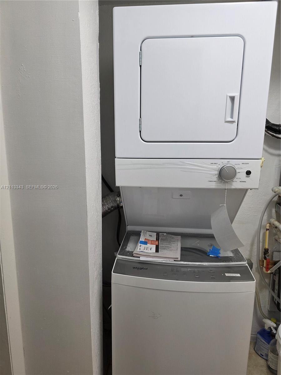 Stacked Whirlpool laundry center featuring a top-loading washer and front-loading dryer