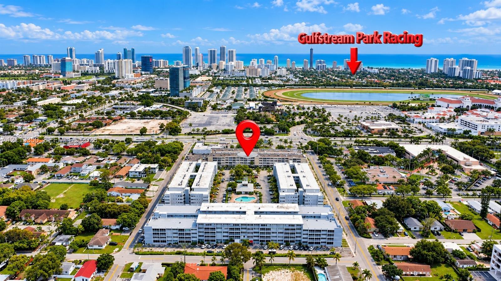 Aerial perspective of a multi-story residential complex featuring a central outdoor swimming pool and perimeter surface parking Aerial perspective of a multi-story residential complex featuring a central outdoor swimming pool and perimeter surface parking