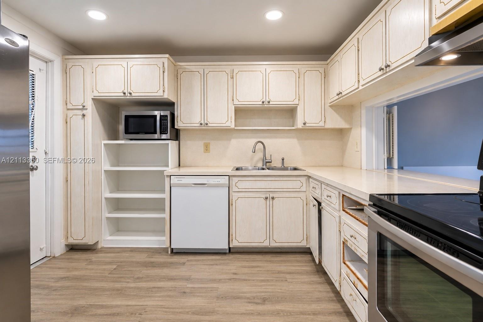 Kitchen featuring light-finish cabinetry, wood-finish flooring, solid-surface countertops, recessed lighting, and stainless steel appliances