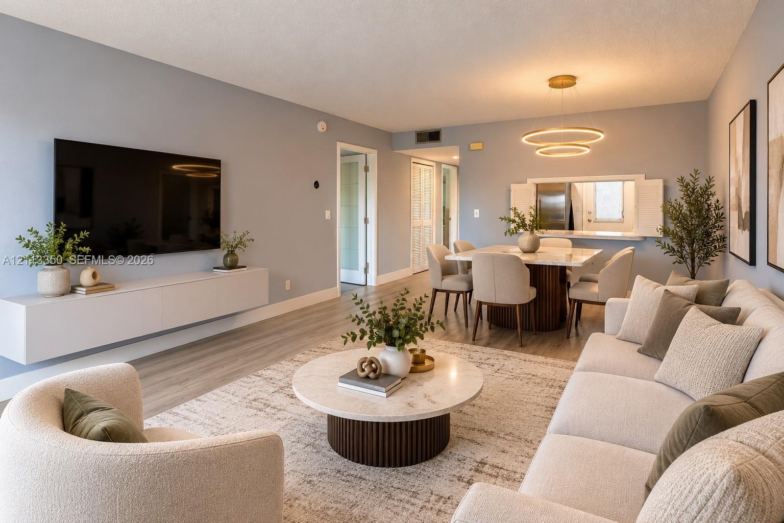 AI RENDERING-Open-concept living space featuring wood-finish flooring, a contemporary dual-ring chandelier, and a wall-mounted floating media console