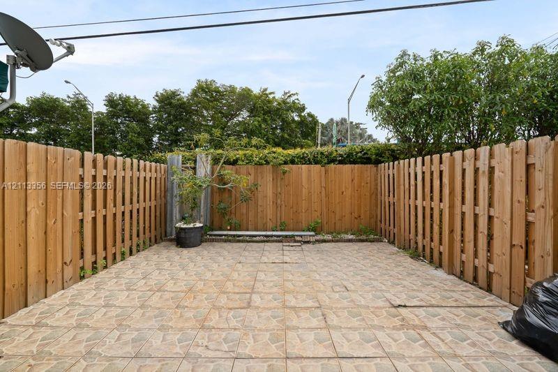 Enclosed courtyard featuring stone-finish paver flooring and full-height wood-slat perimeter fencing
