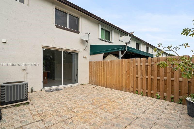 Private patio featuring stone-tiled hardscaping and a wood privacy fence