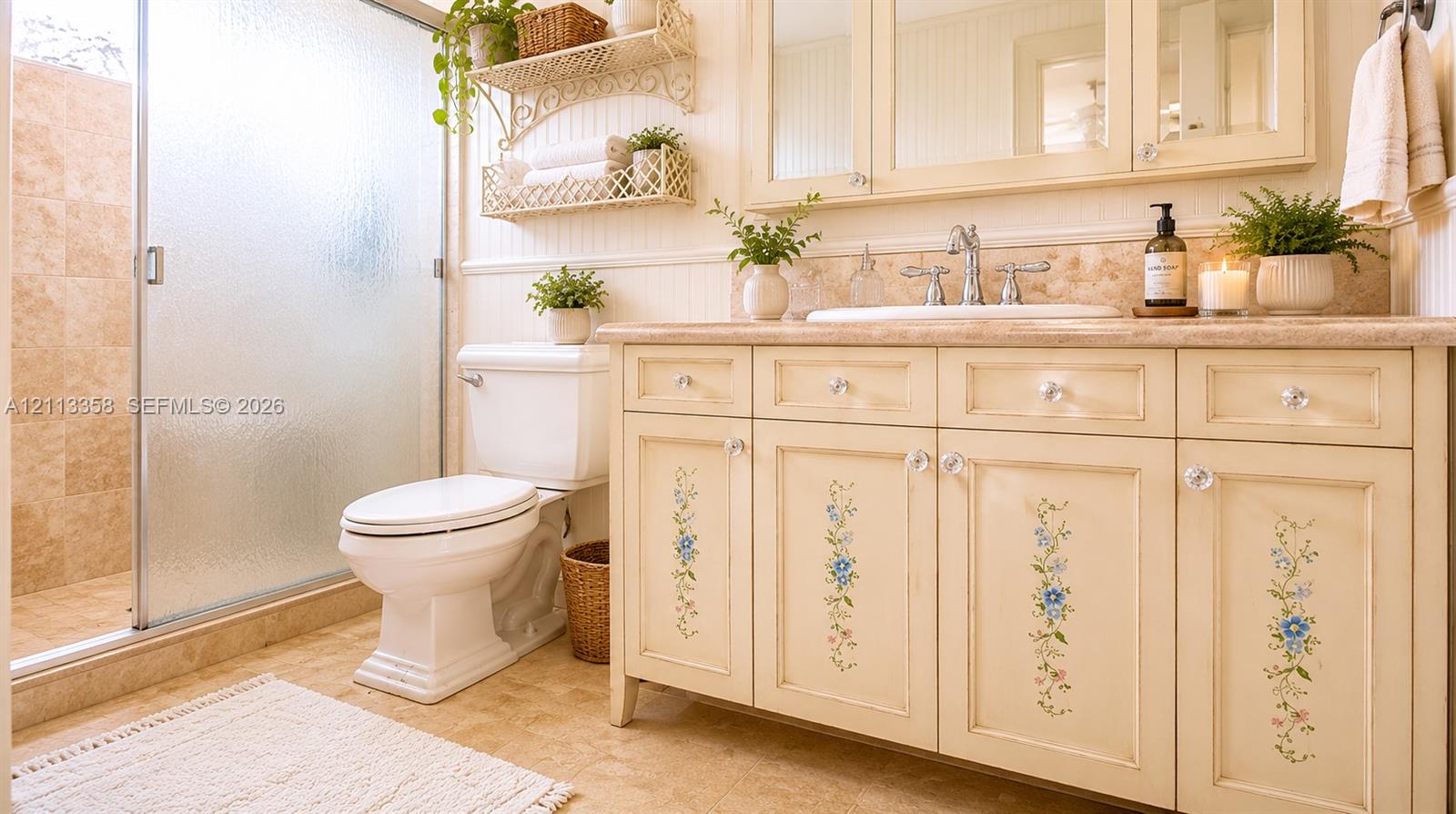 Custom vanity with floral detailing and stone countertop, undermount sink, dual-handle faucet, integrated medicine cabinet with mirrors, and walk-in shower with stone tile surround and sliding glass doors