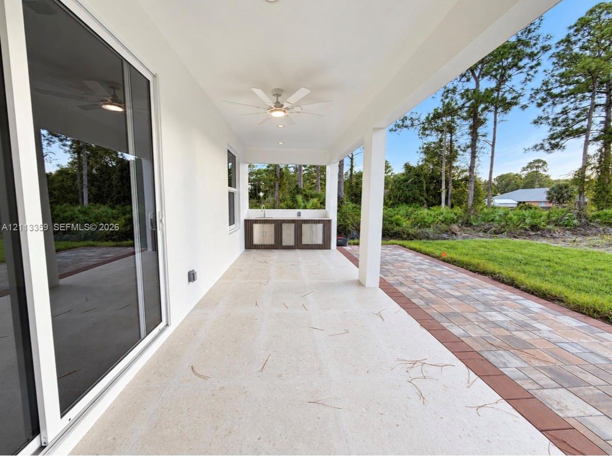 Covered patio featuring a built-in outdoor kitchen, recessed ceiling lighting, a ceiling fan, and paver hardscaping