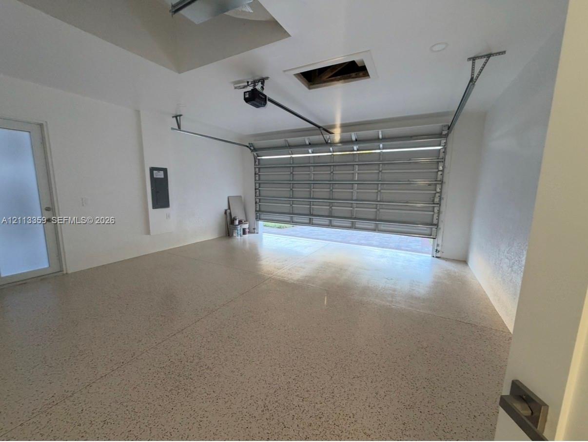 Multi-car garage featuring epoxy-coated flooring, recessed ceiling lighting, and a frosted glass entry door
