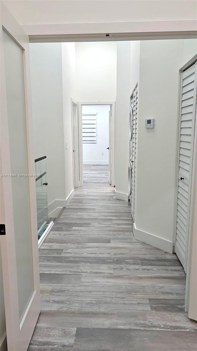 Staircase featuring wood-finish treads, frameless glass railings with black hardware, and vertical slat accent wall paneling over large-format tile flooring