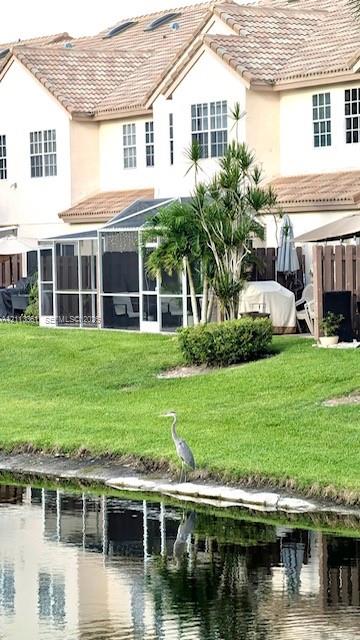 Multi-story exterior featuring multi-pane windows, a shingled roof, screened-in patio, and direct water frontage on a lake