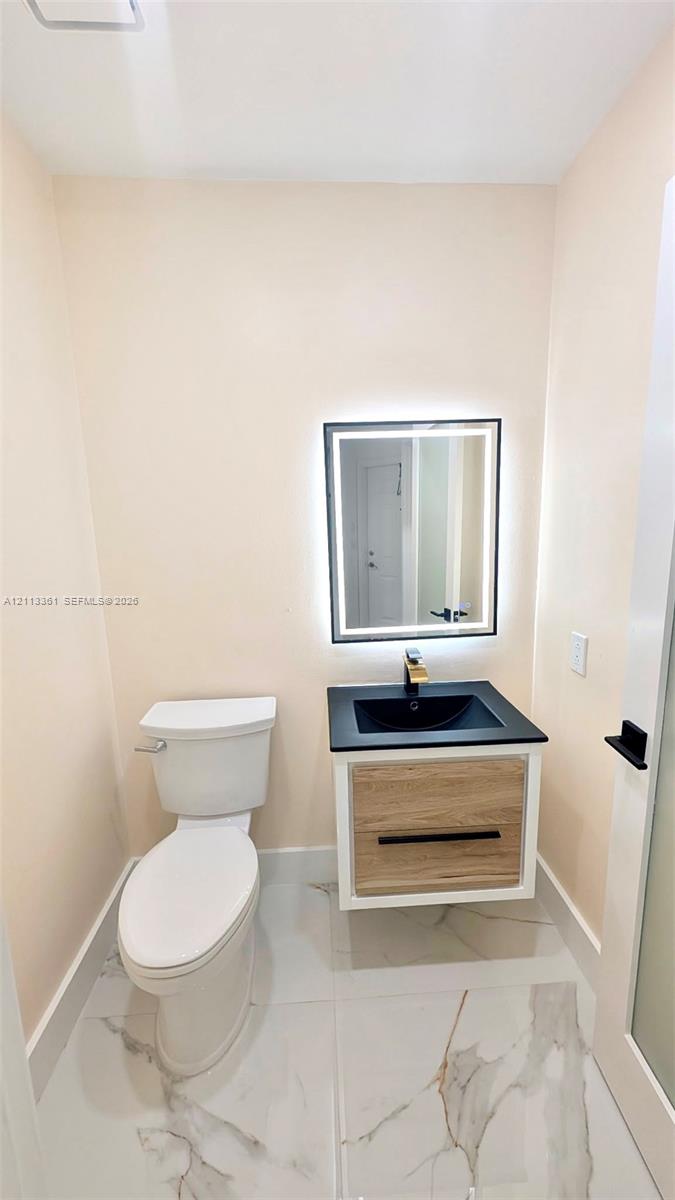 Stacked laundry unit with white louvered bifold closet doors and wood-finish flooring